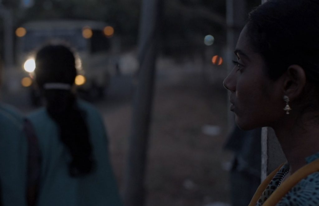 Girl waiting for bus to go to work at the cotton mill, southern India